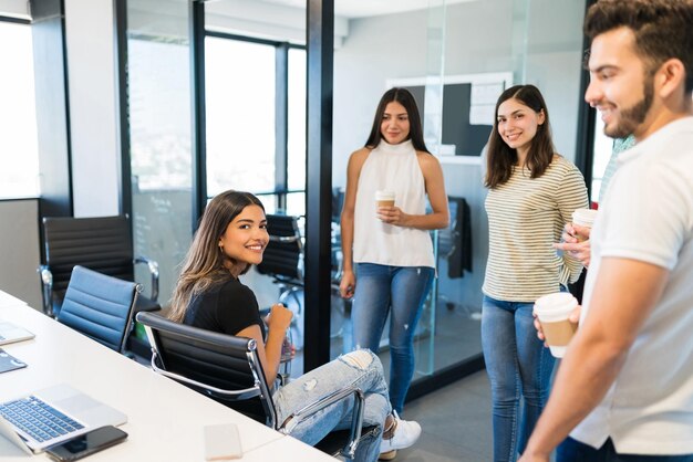 Lächelnde, selbstbewusste Führungskraft mit Team während der Kaffeepause am Arbeitsplatz