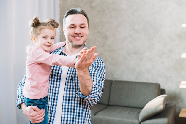 Lächelnde Tochter, die auf der Hand ihres Vaters im Wohnzimmer klatscht