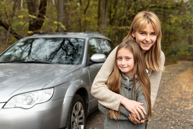 Lächelnde Tochter und Mutter, die im Schrifttyp des Autos aufwerfen