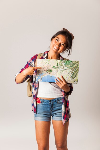 Lächelnde touristische Frau zeigt auf Karte