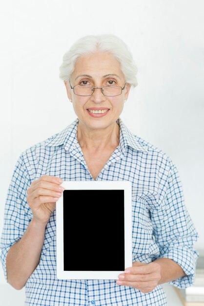 Lächelnde tragende Brillen der älteren Frau, die digitale Tablette mit leerem Bildschirm zeigen