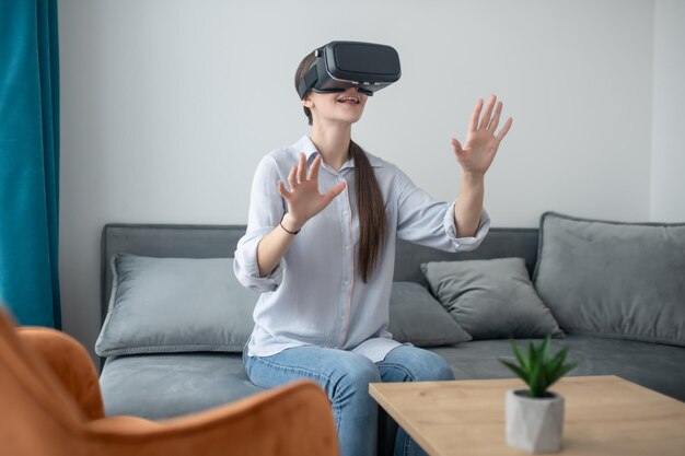 Lächelnde überraschte Frau, die ein 3D-Simulationsspiel spielt