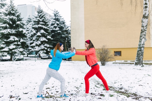 Lächelnde zwei Freundinnen, die draußen an Winter kämpfen