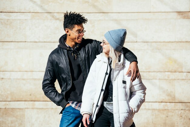 Lächelnde zwischen verschiedenen Rassen junge Paare, die auf der Wand betrachtet einander stehen