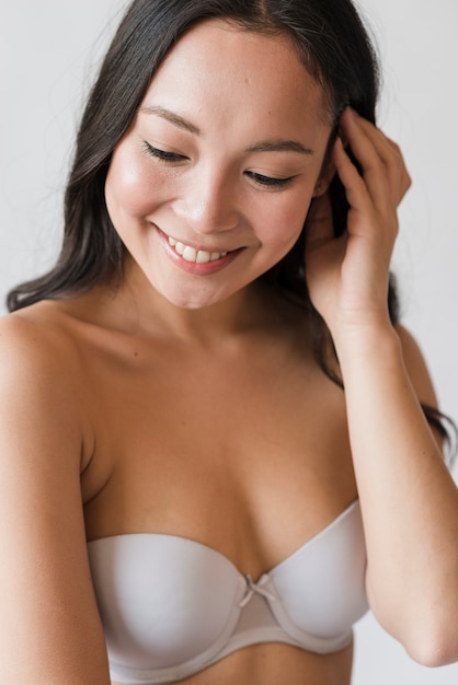 Lächelnder asiatischer junger Brunette in rührendem Haar des BH