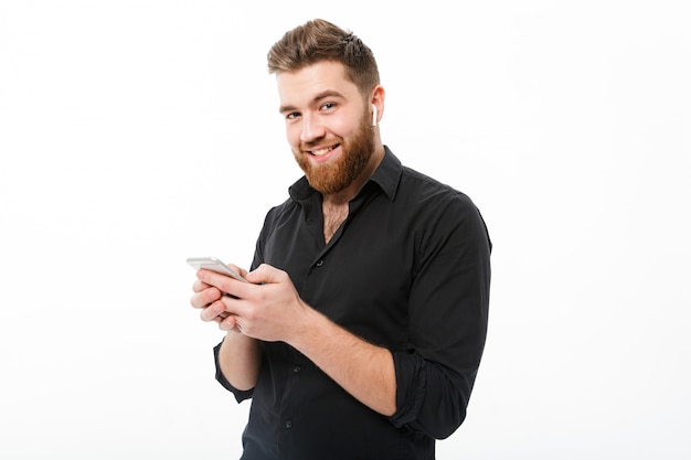 Lächelnder bärtiger Mann im Hemd, das Smartphone hält