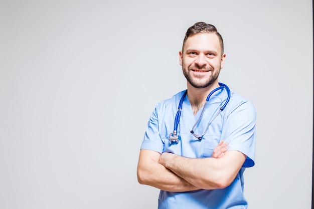 Lächelnder Chirurg mit einem Stethoskop am Hals und an den Armen gekreuzt