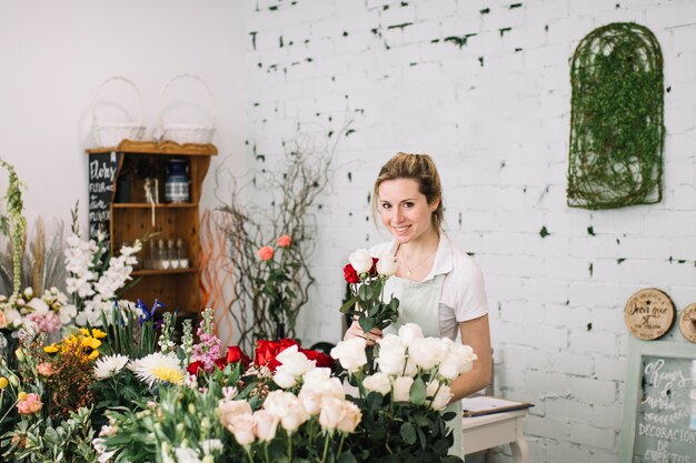 Lächelnder Florist mit dem Blumenstrauß, der Kamera betrachtet