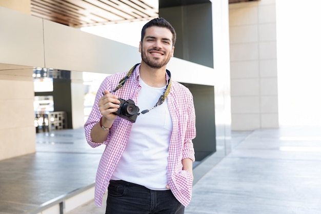 Lächelnder fotograf mit der kamera, die am einkaufszentrum steht