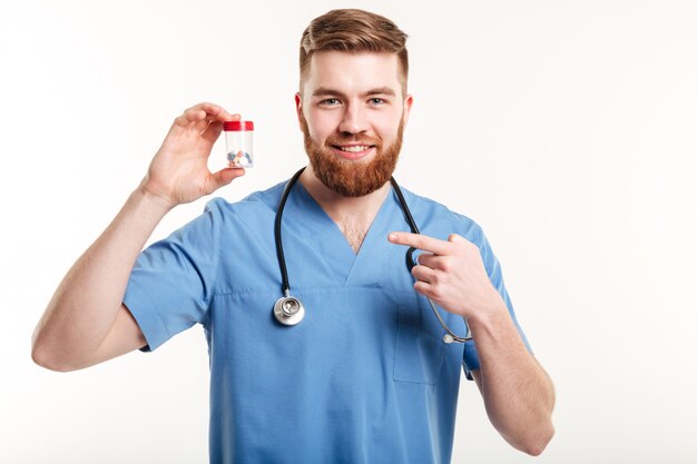 Lächelnder freundlicher Apotheker, der Finger auf Flasche mit Tabletten zeigt