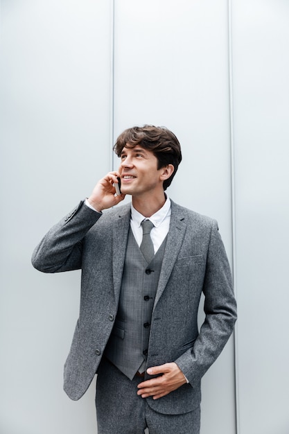 Lächelnder glücklicher Geschäftsmann im Anzug, der ein Handygespräch hat