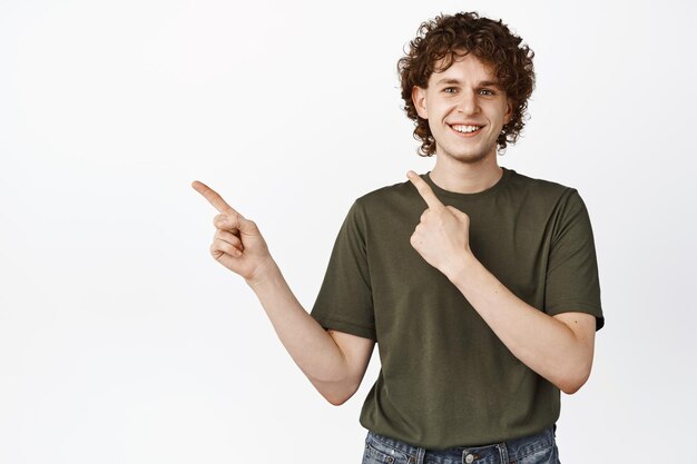 Lächelnder gutaussehender kaukasischer Mann, der mit dem Finger nach links zeigt und das Promo-Verkaufsbanner beiseite zeigt, das über weißem Hintergrund steht