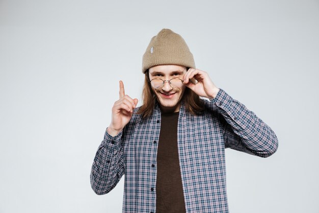 Lächelnder Hipster in der Brille, die nach oben zeigt