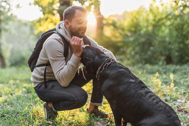 Lächelnder Inhaber, der sein schwarzes Labrador im Wald liebt