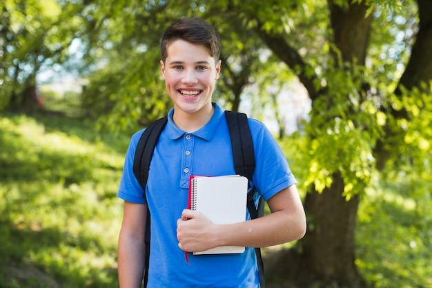 Lächelnder jugendlich Junge mit Notizbüchern