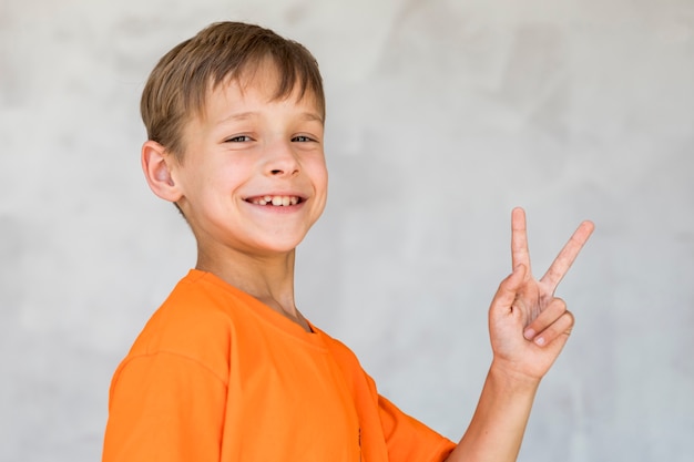 Lächelnder Junge bei der Herstellung des Friedenszeichens