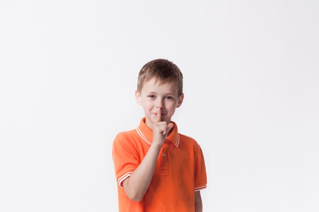 Lächelnder Junge mit dem Finger auf den Lippen, die eine stille Geste machen