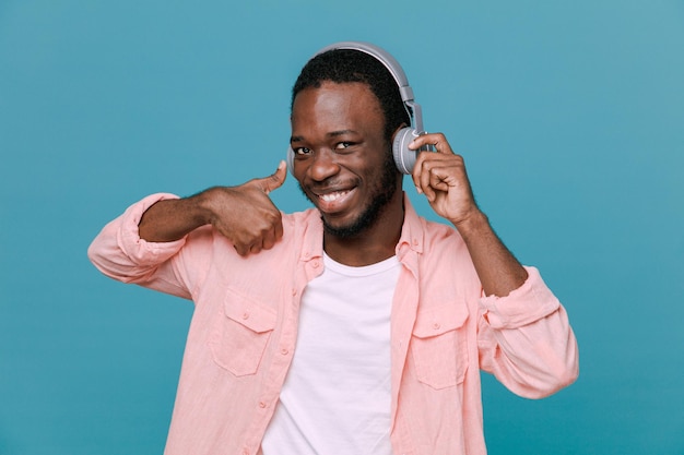 Lächelnder junger Afroamerikaner mit Kopfhörern isoliert auf blauem Hintergrund