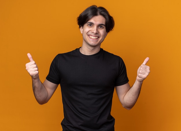 Lächelnder junger gutaussehender Kerl mit schwarzem T-Shirt mit Daumen nach oben isoliert auf oranger Wand