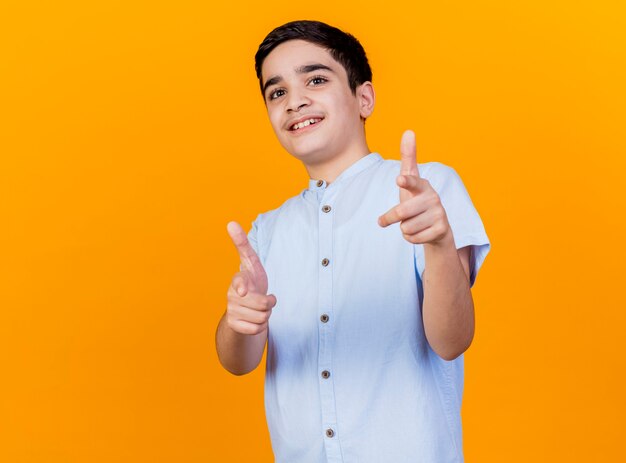 Lächelnder junger kaukasischer Junge, der Kamera betrachtet, die Sie Geste lokalisiert auf orange Hintergrund mit Kopienraum tut
