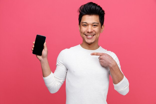 Lächelnder junger Mann, der auf Mobiltelefon hält und zeigt