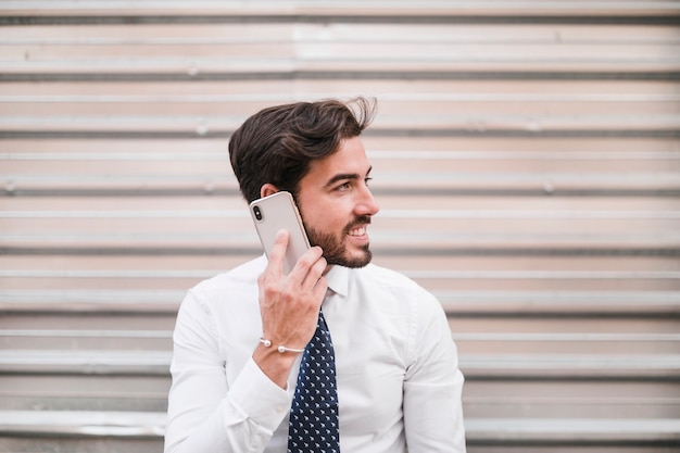 Lächelnder junger Mann, der auf Smartphone spricht