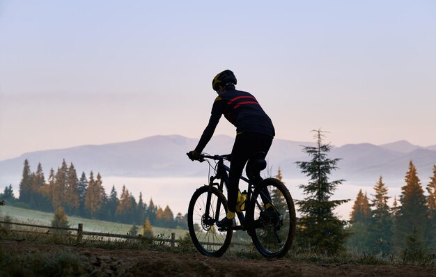 Lächelnder junger Mann, der Fahrrad auf der Bergstraße fährt