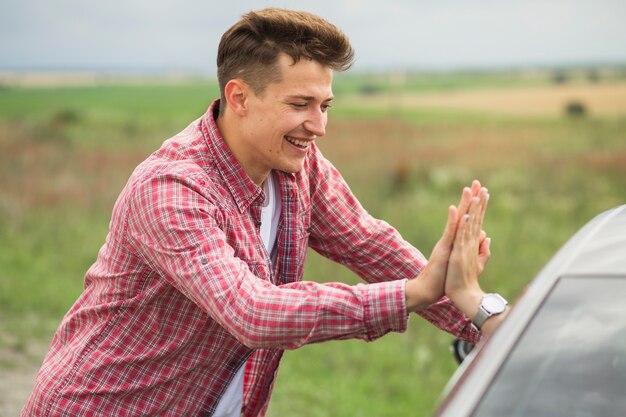 Lächelnder junger Mann, der ihrem Freund Hoch fünf gibt, der im Auto sitzt