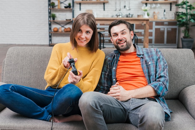 Kostenloses Foto lächelnder junger mann, der mit ihrer frau spielt videospiel sitzt