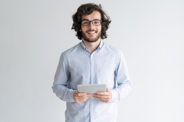 Lächelnder junger Mann, der Tablet-Computer steht und hält