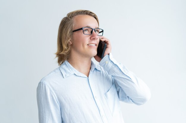 Lächelnder junger Mann, der um Smartphone ersucht