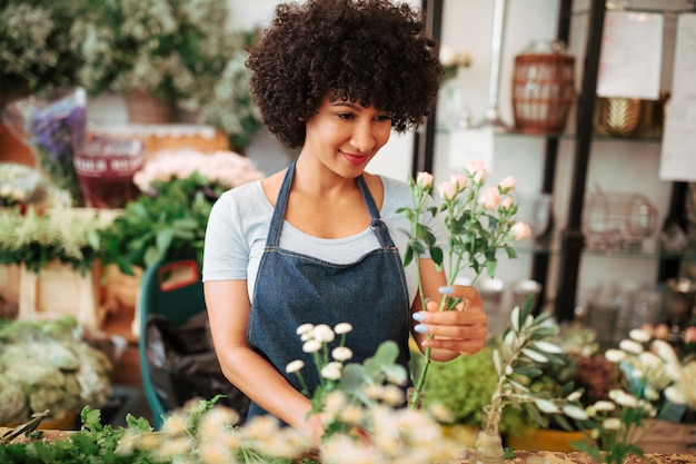 Lächelnder junger weiblicher Florist, der Blumen im Shop anordnet