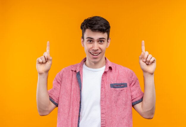 Lächelnder kaukasischer junger Mann, der rosa Hemd trägt, zeigt auf lokalisierten orange Hintergrund