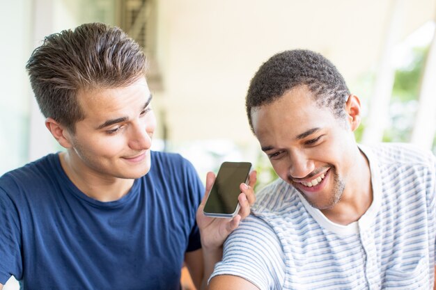 Lächelnder Kerl, der Aufzeichnung am Telefon spielt, um Freund zu zeigen