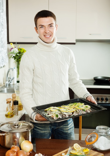 Lächelnder Kerl, der Forellenfische in der Bratwanne kocht