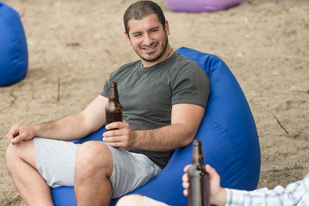 Lächelnder Kerl mit Bier, das nahe Freund stillsteht