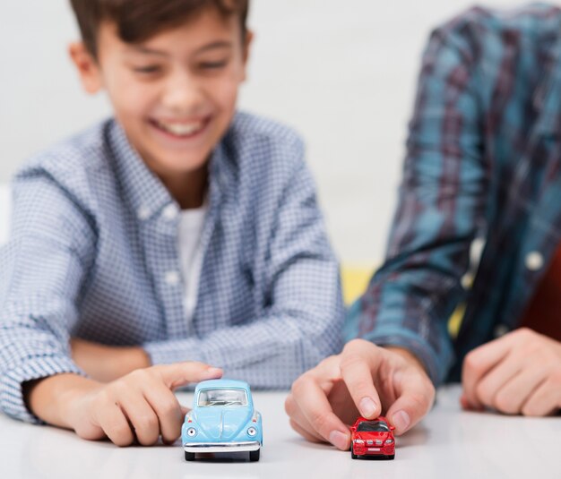 Lächelnder kleiner Junge, der mit Spielzeugautos spielt