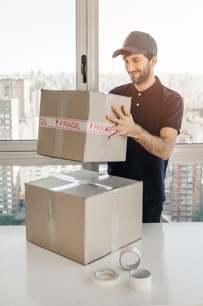 Kostenloses Foto lächelnder lieferer, der paket hält