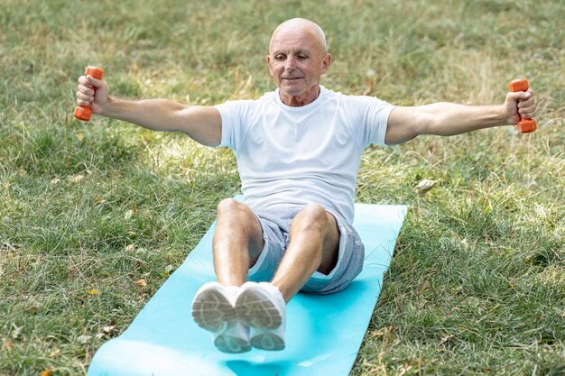 Lächelnder Ältester, der auf Yogamatte ausarbeitet