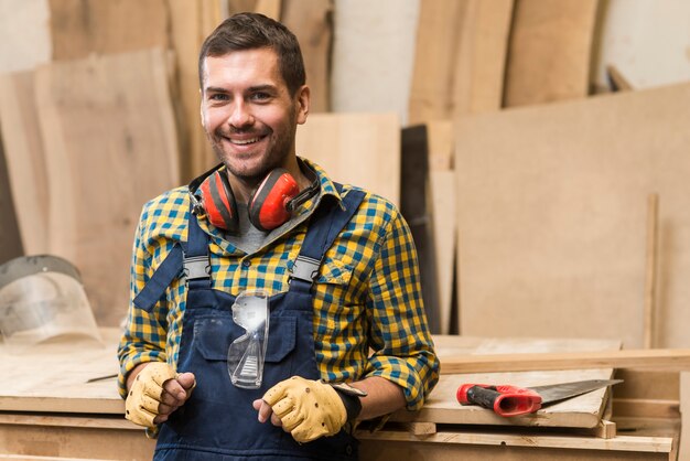 Lächelnder männlicher Tischler, der vor Werktisch steht