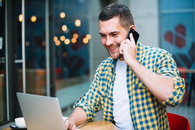 Lächelnder Mann am Telefon, das in der Cafeteria sich entspannt