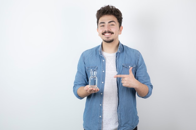 lächelnder Mann, der ein Glas Wasser auf Weiß hält.