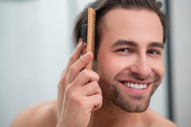 Lächelnder Mann, der Haare frisiert und zufrieden aussieht