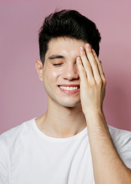 Lächelnder Mann, der halbes Gesicht mit der Hand bedeckt