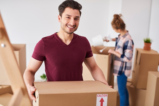 Lächelnder Mann, der in ein neues Zuhause einzieht und seine Sachen auspackt