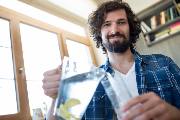 Lächelnder Mann gießt Limonade im Glas