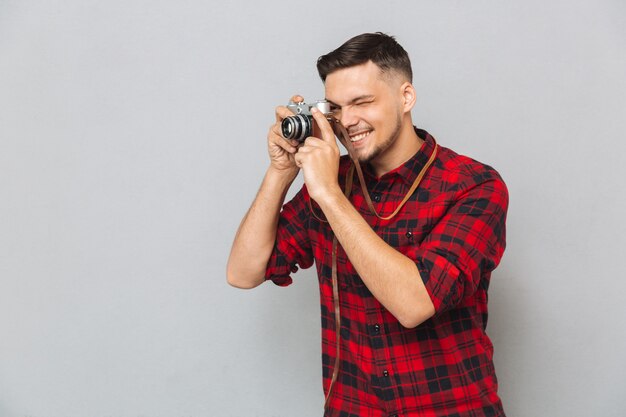 Lächelnder Mann im Hemd, das Foto auf Retro-Kamera macht