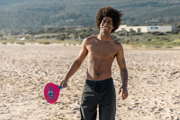 Kostenloses Foto lächelnder mann mit dem tennisschläger, der kamera betrachtet