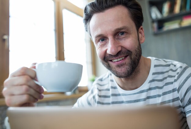 Lächelnder Mann mit einer Tasse Kaffee in der Kaffeestube halten