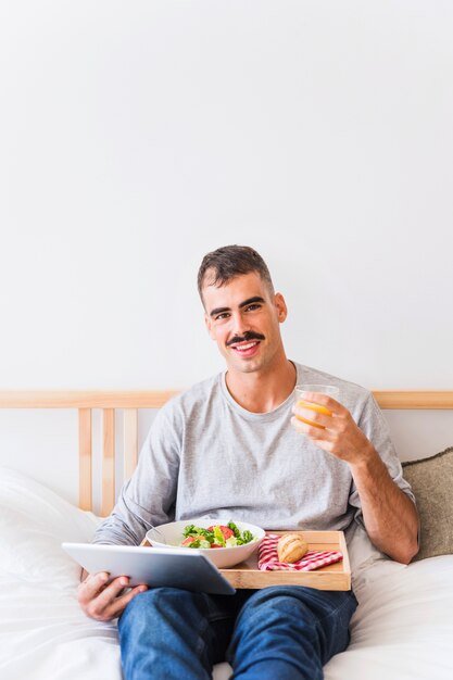 Lächelnder Mann mit gesundem Lebensmittel und Tablette